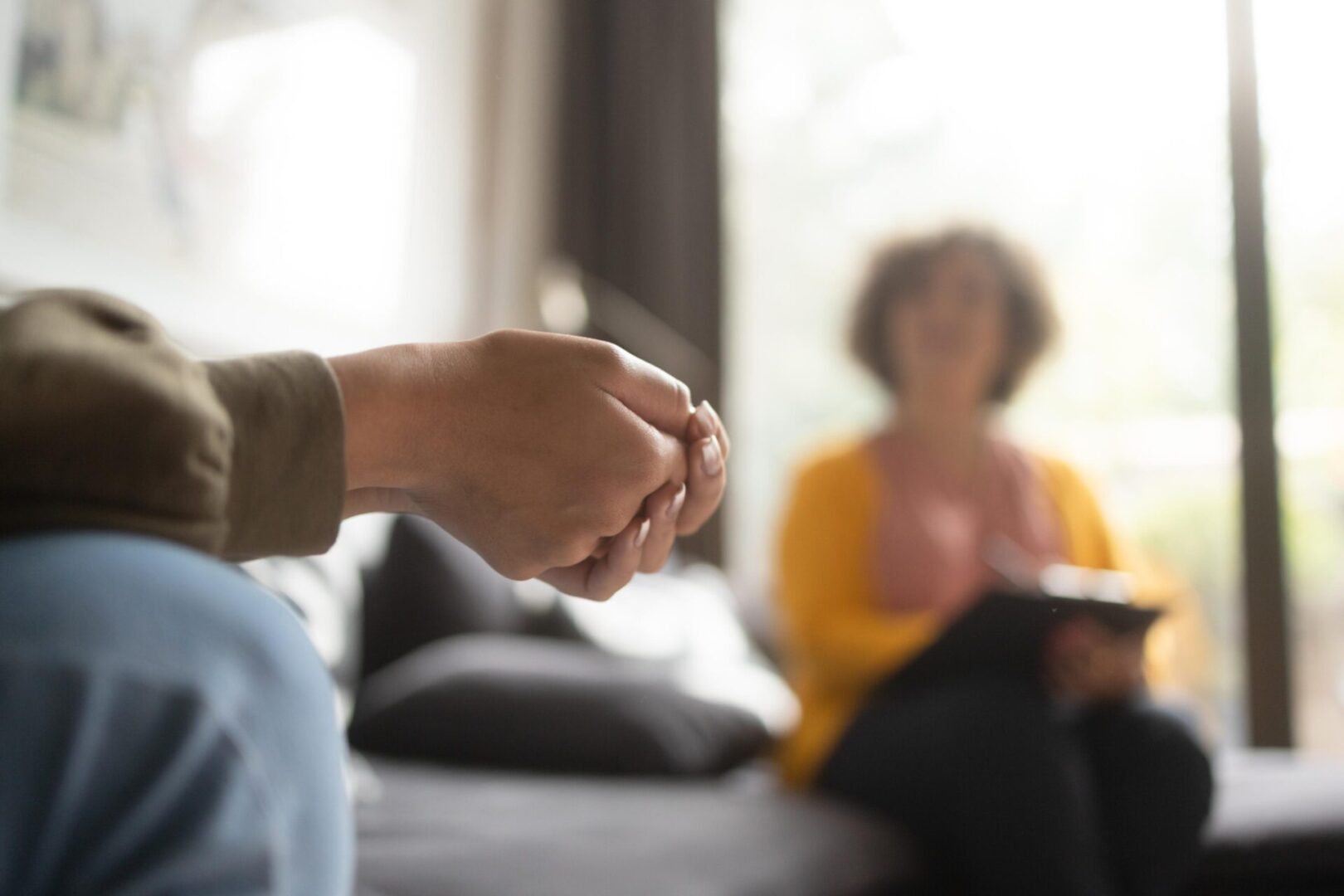 Hands clasped during therapy conversation